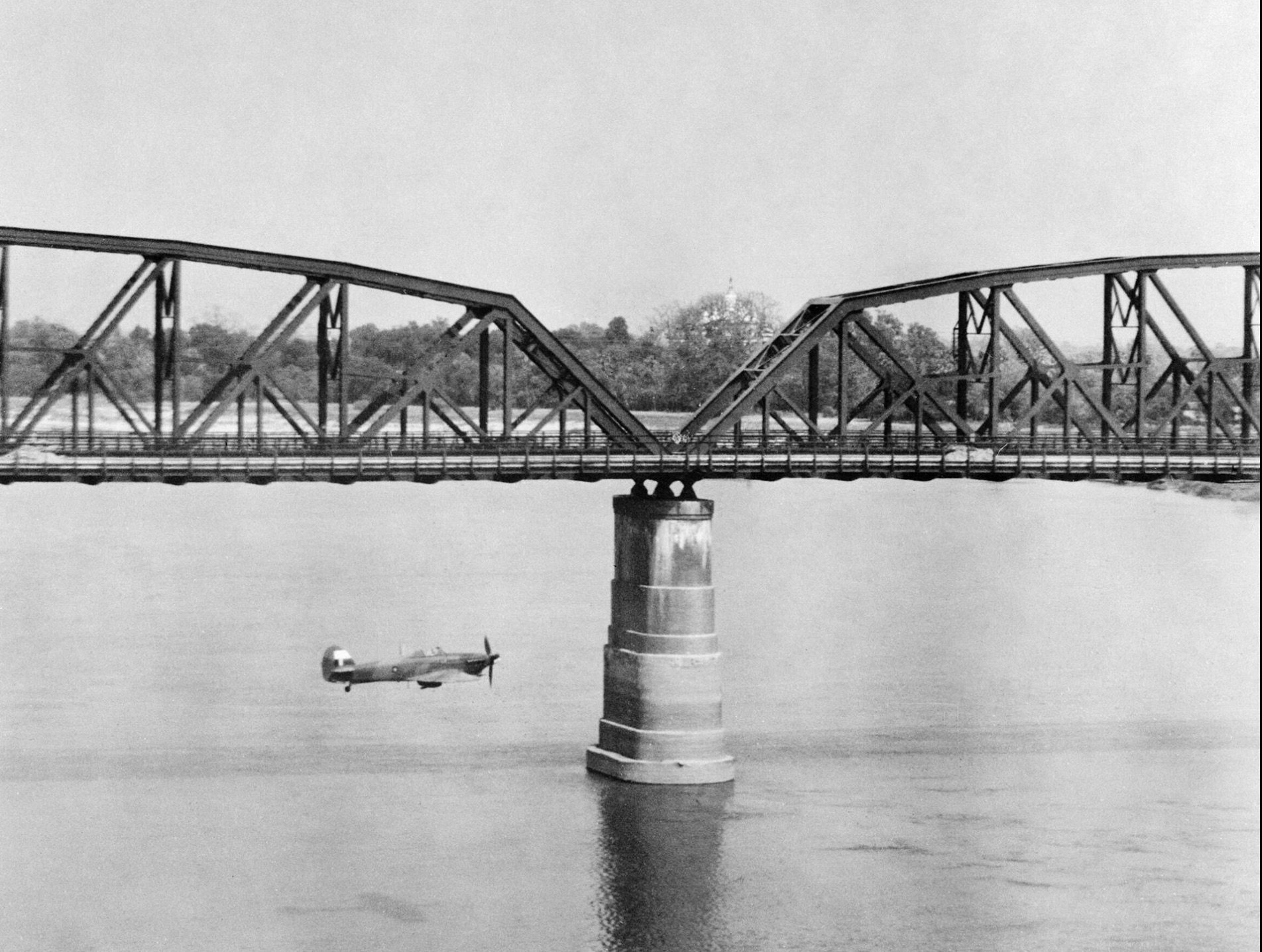 An RAF Hawker Hurricane Mk IIC flies alongside Ava Bridge, which spans the Irrawaddy River near Mandalay, Burma. 